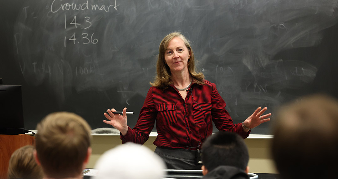 professor standing in front of a chalkboard teaching